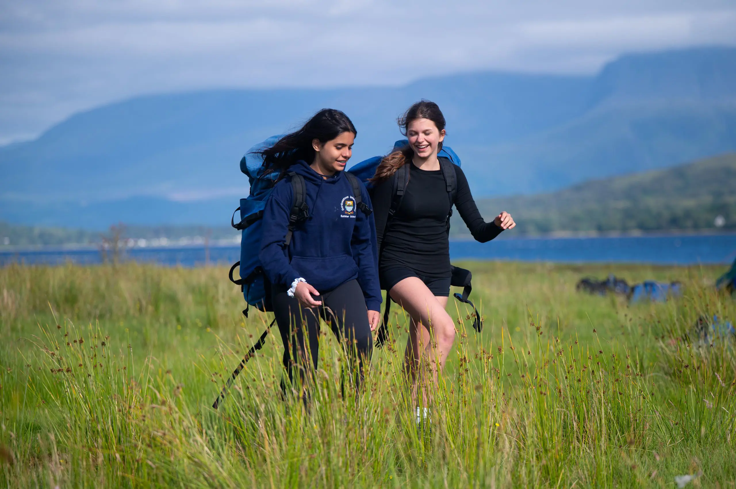 Two students on Gordonstoun International Summer School Camp in the Scottish Mountains walking through long grass
